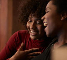 Dos mujeres sonriendo y abrazándose.